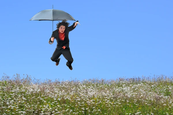 Бизнесмен прыгает через травяной холм — стоковое фото