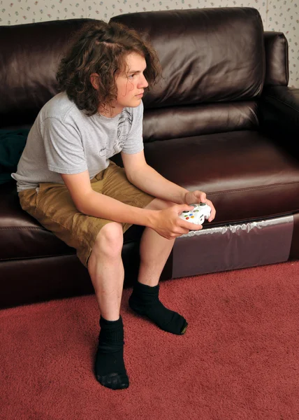 Singeln boy spela videospel på soffan — Stockfoto