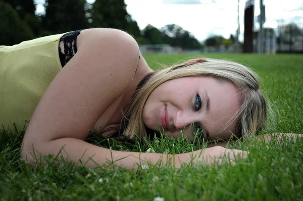 美しい金髪白い白人アダルト 代少女 カメラに笑顔緑の芝生フィールドに敷設のクローズ アップ — ストック写真