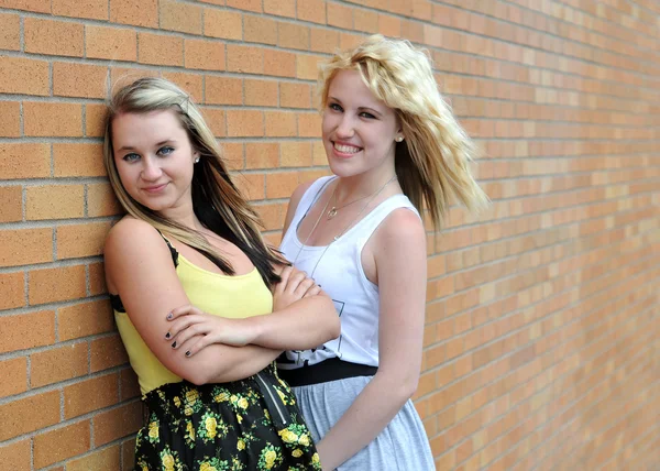 Flickor står bredvid tegel vägg leende — Stockfoto