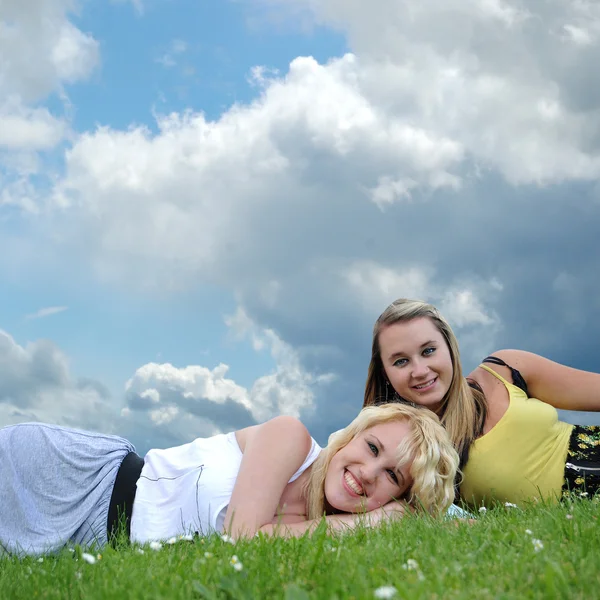 Twee vriendinnen leggen in gras — Stockfoto