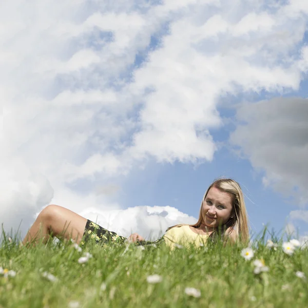 Girl laying on grass hill with copyspace sky — Stock Photo, Image
