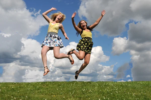 Two girls jumping in grass field — Stock Photo, Image