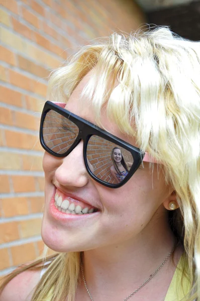 Девушку Улыбающуюся Можно Увидеть Солнечных Очках Подруги Отражающихся Кирпичной Стене — стоковое фото