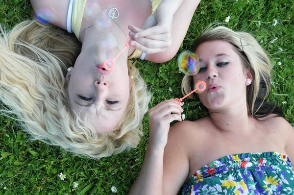 Two Girl Friends Blowing Bubbles in Grass — Stock Photo, Image