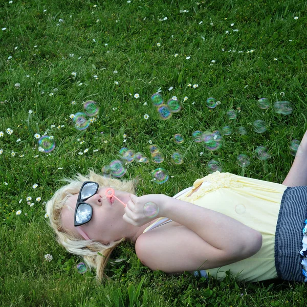 소녀와 그녀의 선글라스에 하늘에 거품을 잔디에 — 스톡 사진
