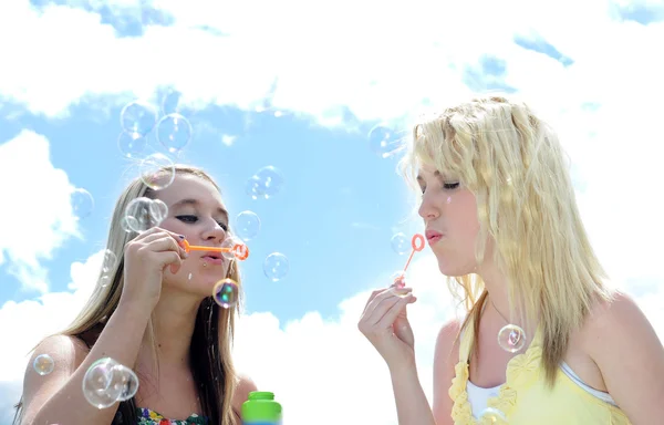 Two girl friends blowing bubbles — Stock Photo, Image