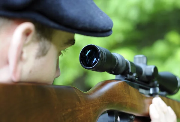 Hombre mirando a través de la mira en una pistola de rifle — Foto de Stock