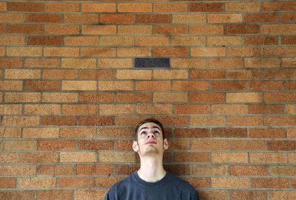Bir Tuğla Duvara Yaslanmış Başının Üstünde Genç Beyaz Erkek Arayan — Stok fotoğraf