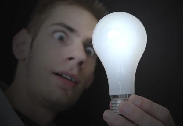 Ung Vuxen Man Håller Upp Glödlampa Och Undersöker Mycket Ljus — Stockfoto