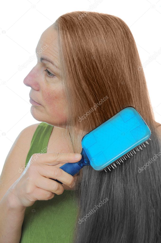Woman combs her hair gray to brown showing the signs of old age and youth
