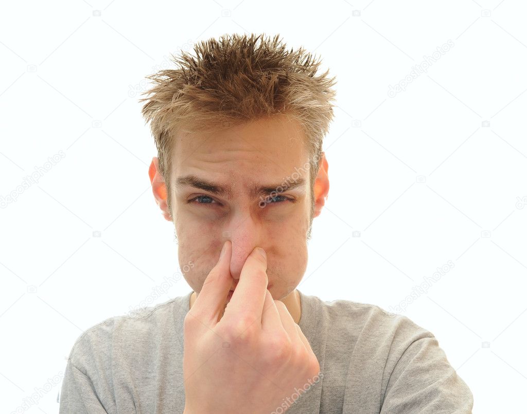 Young adult man tightly holds his hand over his nose in order to plug out the horrible odor he is smelling. Isolated on white background with room for your copy