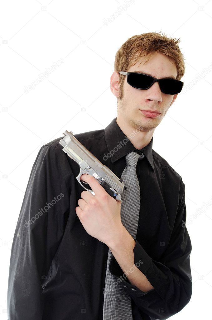 Young man holding up a gun with the focus on his face. He is wearing sunglasses