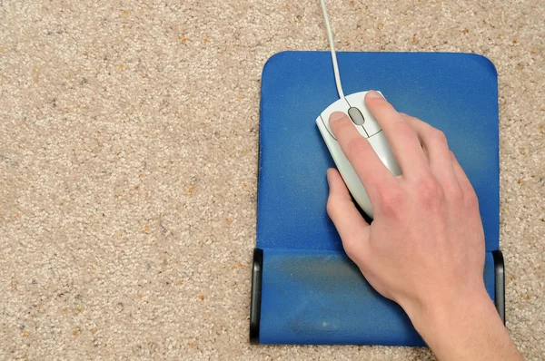 上一个褐色的地毯上蓝色鼠标垫上的鼠标手 — 图库照片