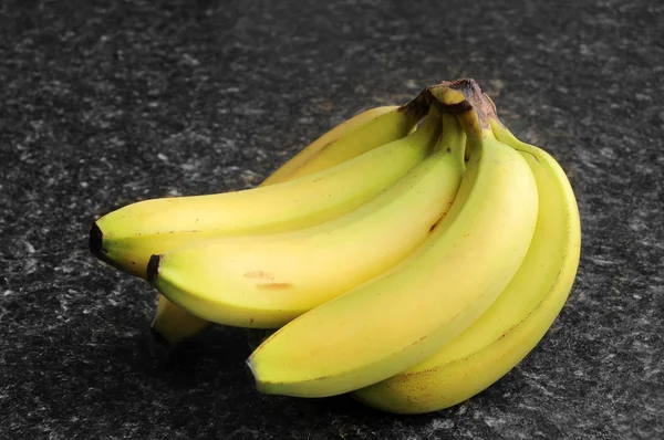 stock image Bananas on a black kitchen counter top.