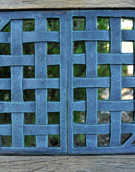 蓝色编织的金属丝网网格图案与模糊背景中的 Foilage — 图库照片
