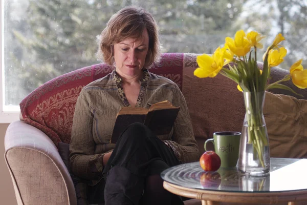 Baby Boomer Woman Reading Book Table Flowers — Stock Photo, Image