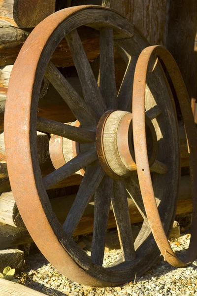 stock image Antique wagon wheels leaning against an old square log barn