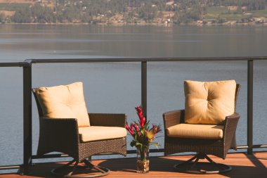 Two deck chairs on a beautiful lakefront home deck in the sunshine. clipart