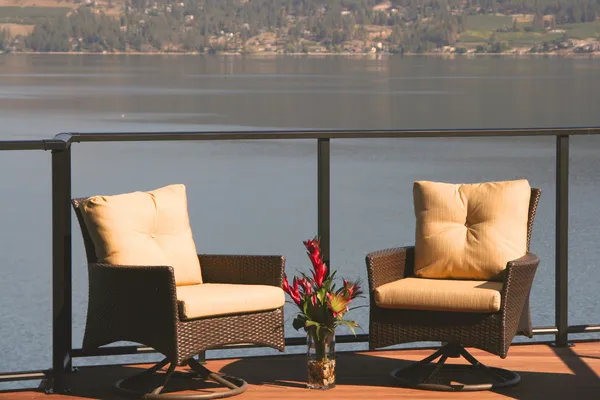 stock image Two deck chairs on a beautiful lakefront home deck in the sunshine.