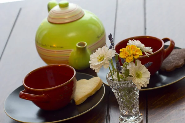 一壶茶用新鲜烤的饼干和鲜花的表 — 图库照片