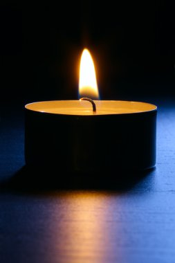 Candle closeup on a dark wooden table in blue back lit. Close up shot with selective focus. Vertical composition. clipart