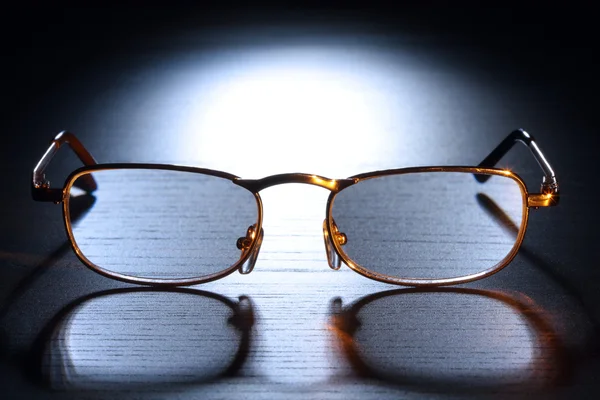 stock image Golden glasses in light beam. Low-key scene.