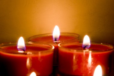 Red church candles burning in subdued lighting clipart