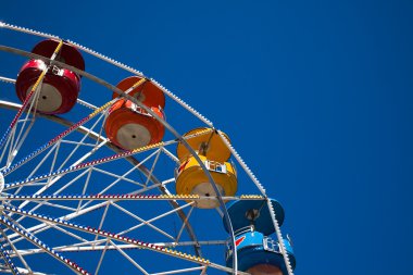 Multi-colored ferris wheel against a blue sky clipart