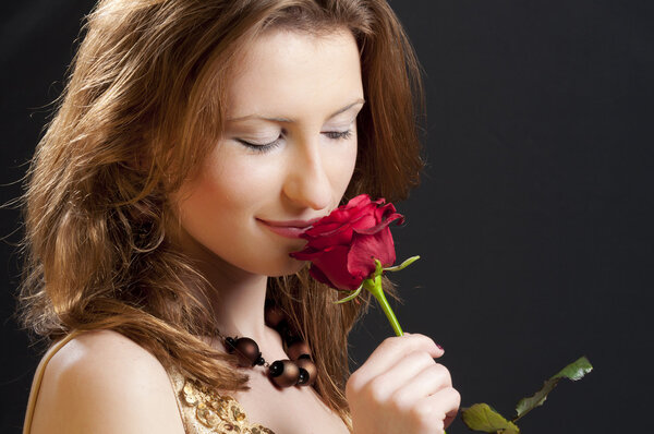 Young girl playing with a red rose recived for valentine's day isolated on a black background