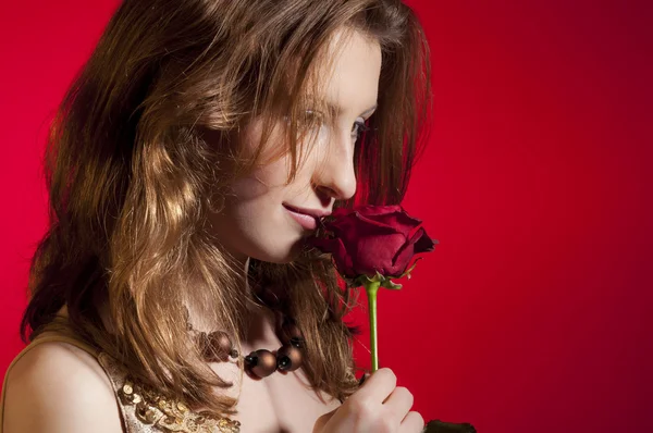 赤の背景に分離されたバレンタインの日に赤いバラのフェージングと遊ぶ若い女の子 — ストック写真