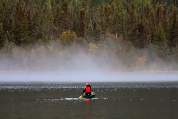 Stock image Man in canoe near morning mist on lake