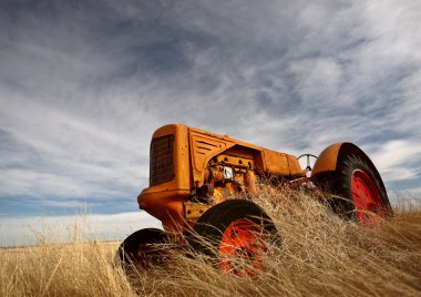 Tumbleweeds piled against abandoned tractor clipart