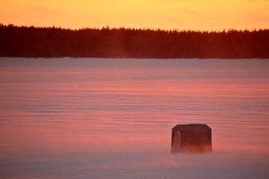 icefishing kulübe günbatımında donmuş göl üzerinde