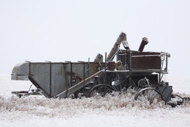 Abandoned antique threshing machine in winter clipart
