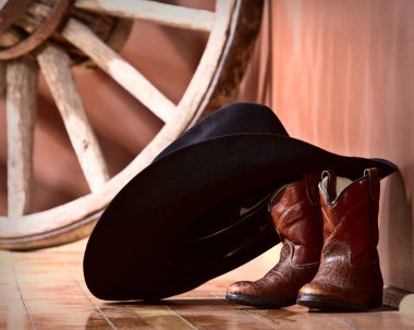 Cowboy hat leaning on small boots clipart