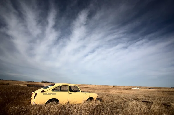 Wispy nuvens sobre abandonado carro de fabricação estrangeira — Fotografia de Stock