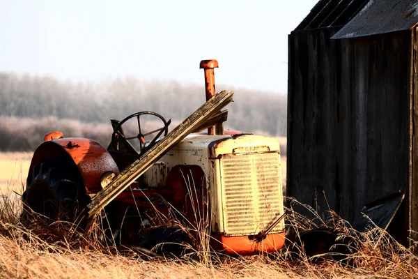 Заброшенный трактор старыми амбарами — стоковое фото