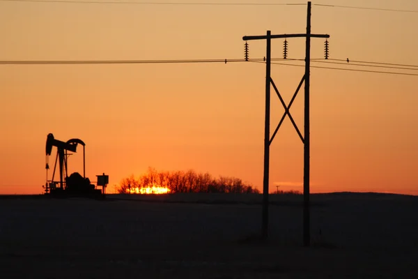 Sol nasce atrás de plataforma de petróleo e linha de energia — Fotografia de Stock