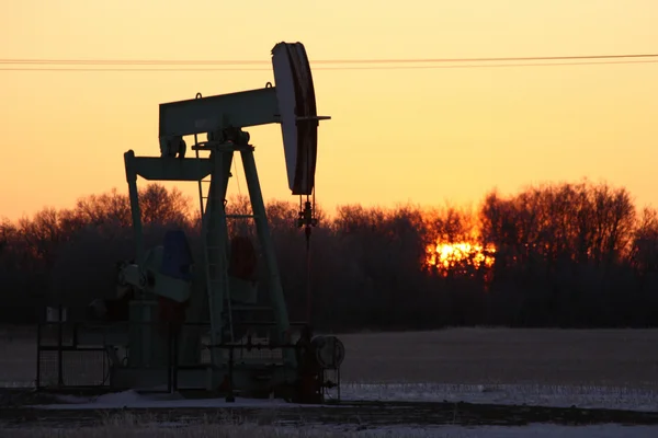 Zon stijgen achter olie pomp jack — Stockfoto