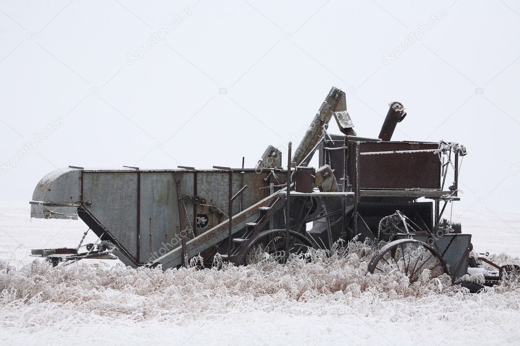 Abandoned antique threshing machine in winter