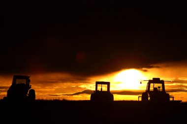 Sunrise behind farm machinery Saskatchewan clipart