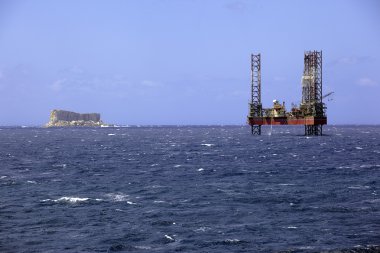 Offshore prospection platform next to a small island in mediterranean sea clipart