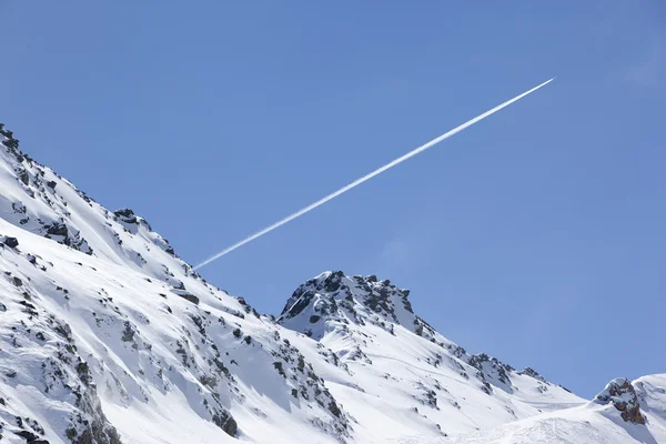 Plane trail over snowy mountain — Stock Photo, Image