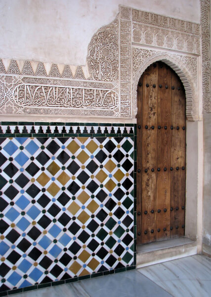 Carved islamic wall decoration filled with colourful tiles, Alhambra, Granada, Spain.