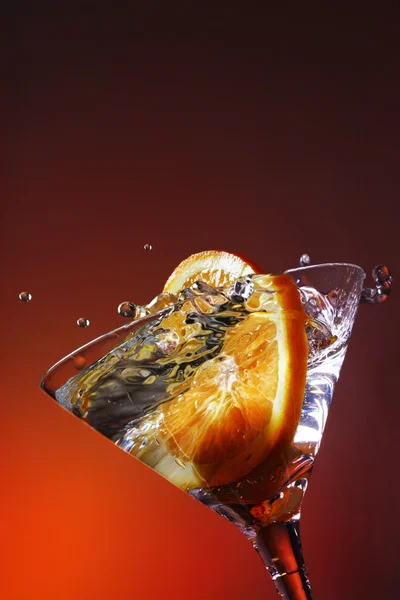 Orangenscheibe spritzt in ein Cocktailglas — Stockfoto