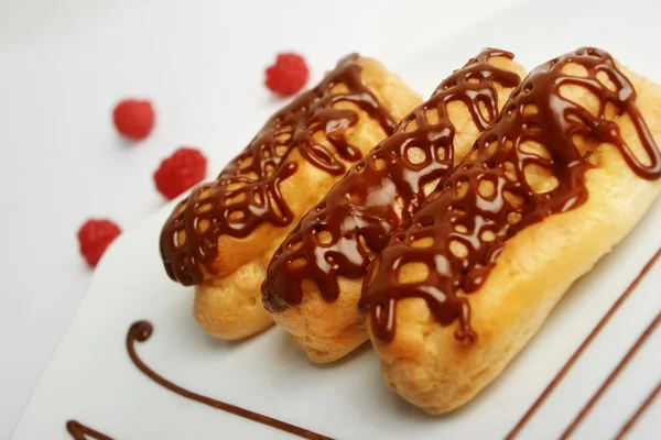 Eclairs Plate Closeup Chocolate Syrup Raspberries Background — Stock Photo, Image