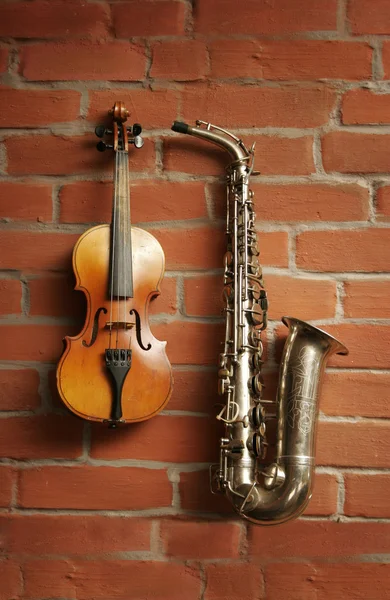 stock image Violin & saxophone over red brick wall