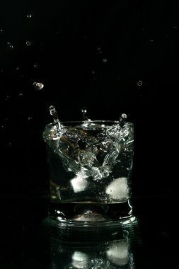 Alcohol splash on black background close up clipart