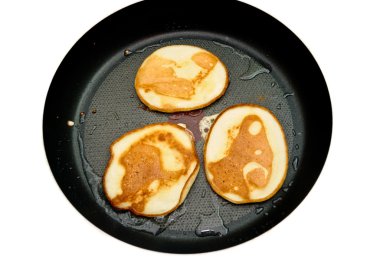 Fritters on a frying pan pancakes on the griddle on the white isolated back clipart